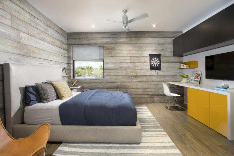 Teen boy's room with wood-paneled walls, modern furniture, and yellow storage cabinets.