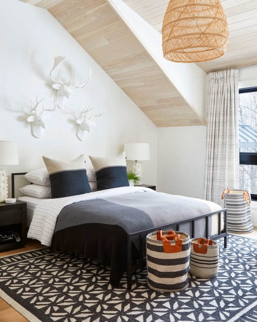 Teen boy's bedroom with black and white decor, geometric patterns, and wall-mounted animal head sculptures.