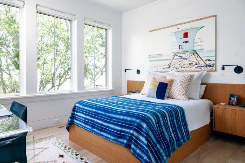 Teen boy's room with large windows, coastal decor, and a blue and white color scheme.