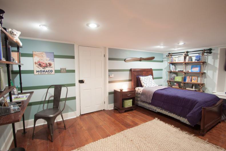 Teen boy's room with horizontal green and blue stripes, dark wood furniture, and industrial shelving.