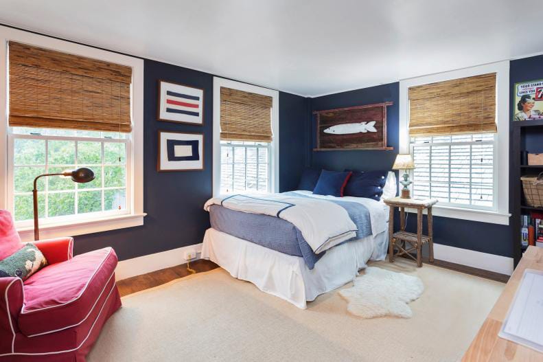 Teen boy's room with nautical decor, deep blue walls, and natural woven blinds.