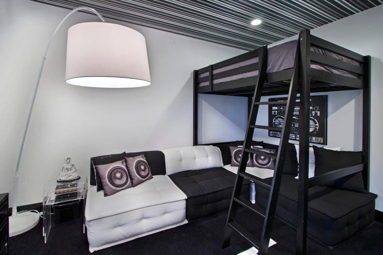 Teen boy's room with a loft bed, sectional sofa, and a monochrome color scheme.