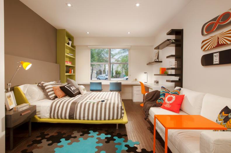 Teen boy's room with bold orange and green accents, skateboard wall art, and a puzzle piece rug.