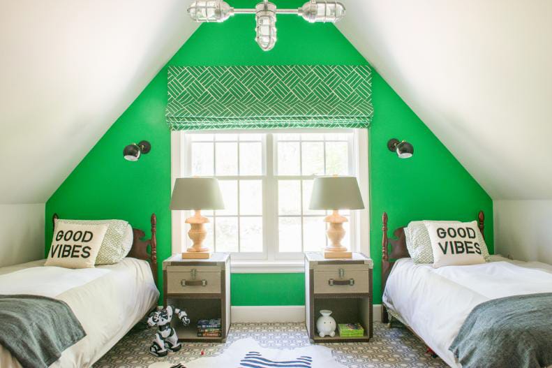 Bright green room with twin beds and "Good Vibes" pillows, featuring matching bedside tables and lamps.