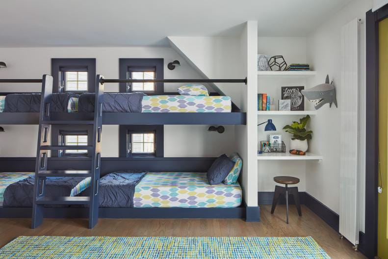 Modern room with custom-built bunk beds, navy blue accents, and built-in shelves.