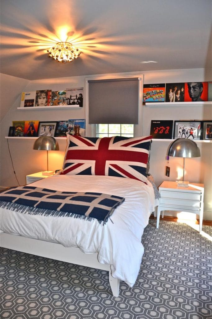 Loft with Union Jack bedspread, vinyl records on wall-mounted shelves, and artistic ceiling light.