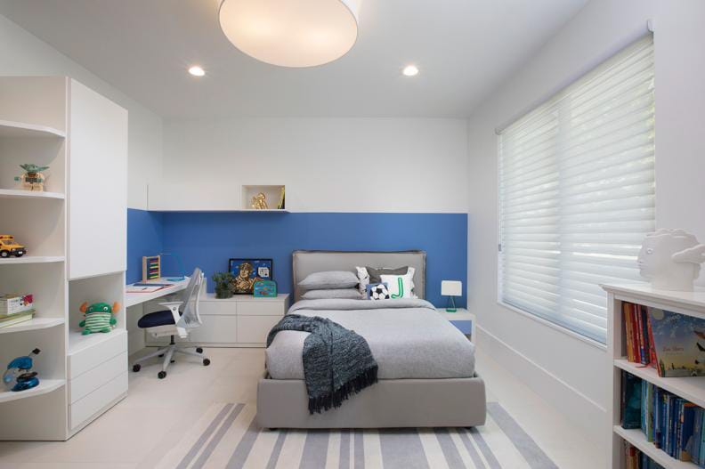 Modern bedroom with gray and blue color scheme, featuring a blue accent wall and minimalist furniture.