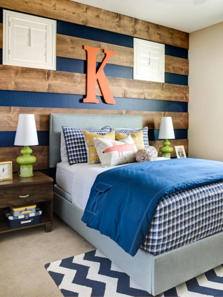 Bedroom with a navy accent wall and wood paneling, featuring a large initial on the wall.