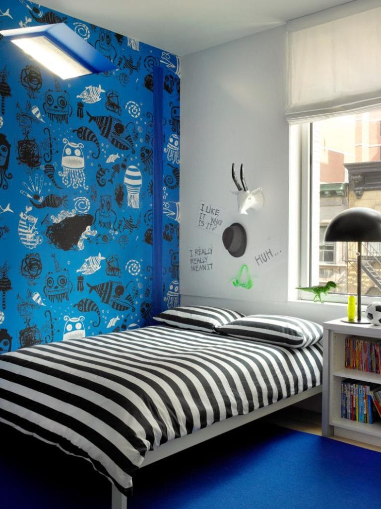 Blue wall with quirky art and black-and-white striped bedding, creating a fun and modern space.