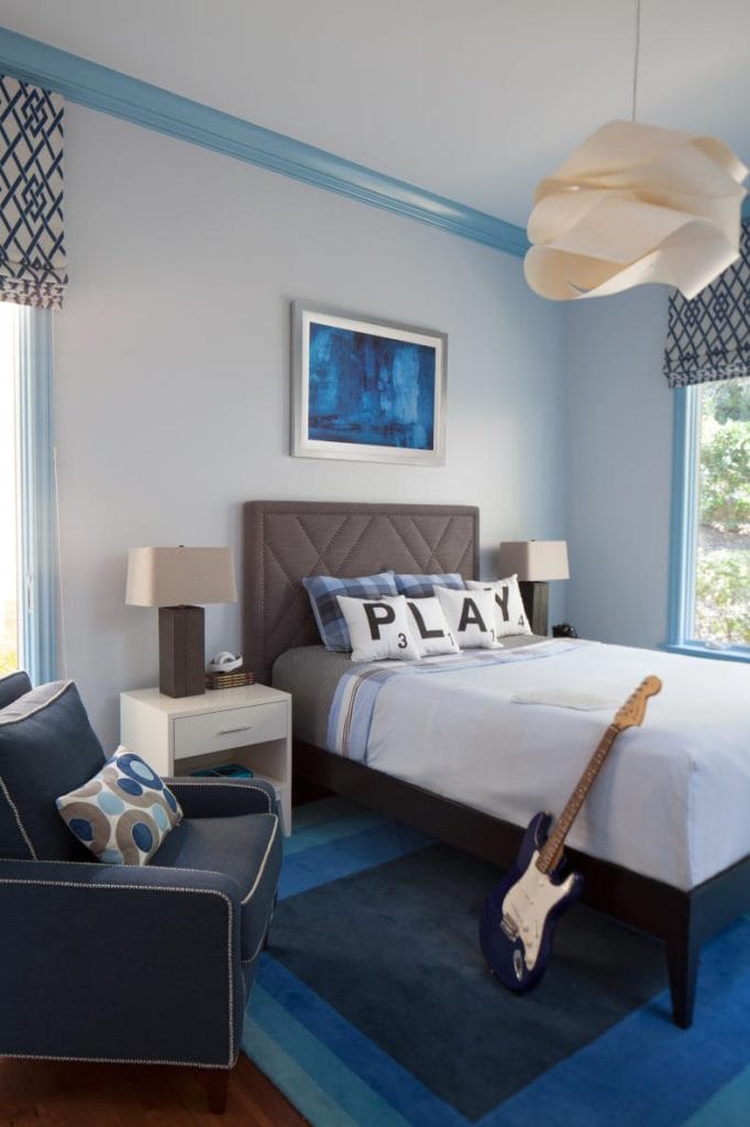 A modern teen boy's bedroom with Scrabble pillows and a guitar in the corner.