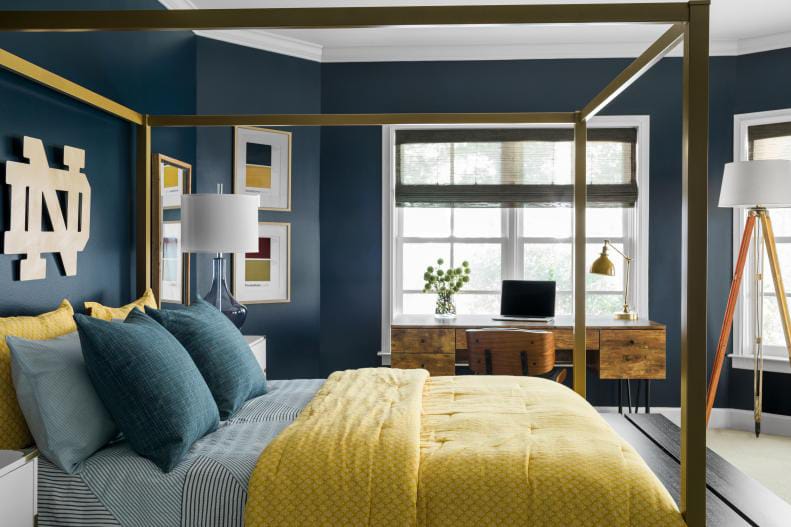 A navy and gold-themed teen bedroom with a large bed, window seat, and modern decor.