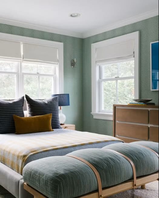 Teen boy's bedroom with soft green walls, blue accents, and a large window providing natural light.