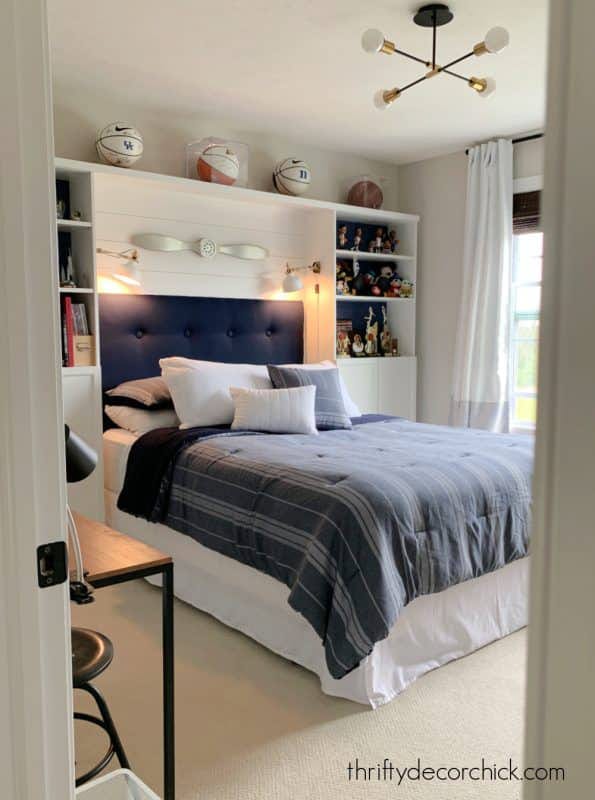 A cozy bedroom with a navy and white color scheme, built-in storage, and sports decor.