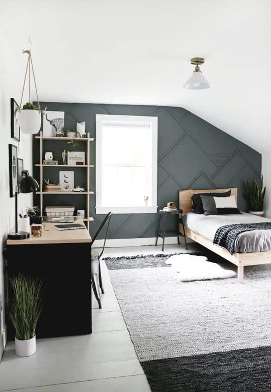 A minimalist bedroom with a green accent wall, workspace, and simple furnishings.