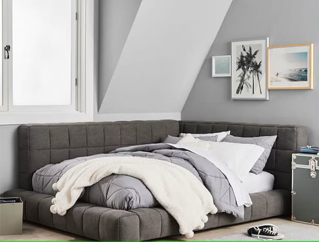 A cozy bedroom with a low-profile tufted bed and gray walls.