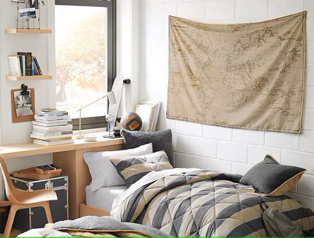 A bedroom with a bed, study desk, and a map on the wall.