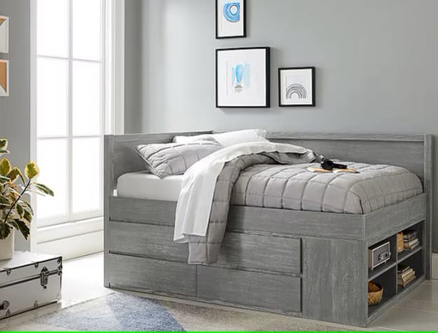 Gray bed with built-in storage drawers and minimalist wall decor in a teen boy's room.