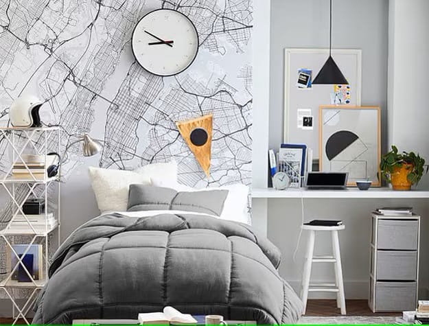 Gray bed with map wall art and a study area in a teen boy's room.