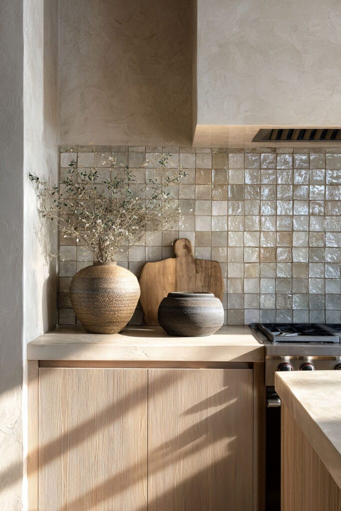 neutral glossy tile backsplash with plaster walls and light wood cabinets in an organic modern kitchen design