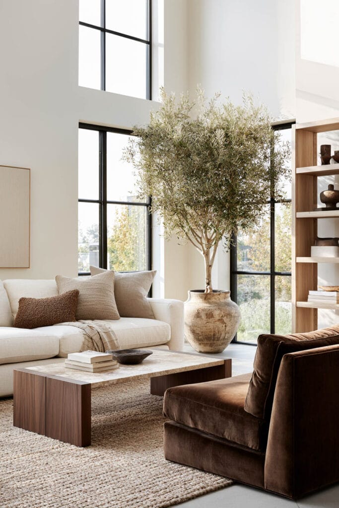 Bright living room with chocolate brown velvet armchair, cream sofa, warm wood furniture, neutral textures, and natural light.